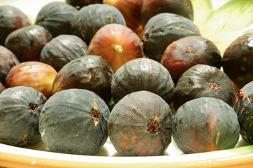 Ripe sweet figs. Figs fruit on a plate close up/macro. Healthy mediterranean fig fruit. Top view. Selective focus on the top figs slice in the bowl. Cut figs. Sliced fresh fruits.