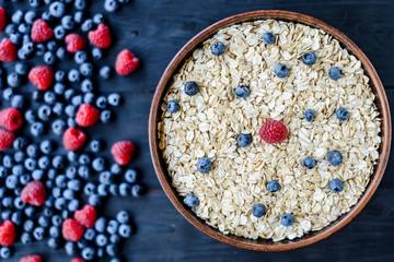 Top view plate with oatmeal and berries on a dark background. Fitness.