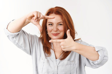 Catching inspiration. Optimistic enthusiastic mature redhead caucasian woman make frames gesture...
