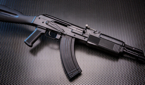 FM AK rifle on metal grid background.