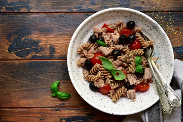 Whole wheat pasta fusilli with tuna, tomato and black olives. Top view with copy space.