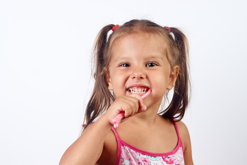 Close-up portrait of a beautiful toddler smiling while brushing her teeth