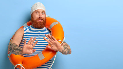 Nervous bearded ginger guy makes refusal gesture, palms outstretched afraids of swimming by himself...
