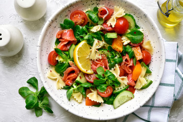 Pasta salad with vegetables and salted salmon. Top view with copy space.