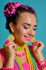 Lovely girl with a multi-colored braids hairstyle and bright make-up, posing in studio against a blue background.