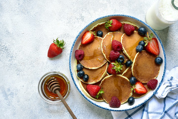 Homemade delicious pancakes with fresh berries and honey. Top view with copy space.