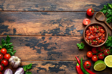Tomato salsa (salsa roja) - traditional mexican sauce  with ingredients for making. Top view with copy space.