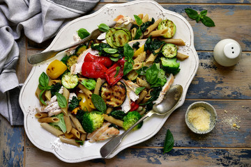 Wholegrain penne pasta with grilled vegetables and chicken breast.Top view.