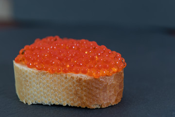 Red caviar with white bread on the grey stone background