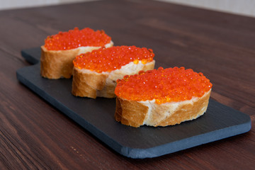 Set of three sandwiches with red caviar on the grey stone background