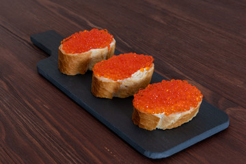 Set of three sandwiches with red caviar on the grey stone background