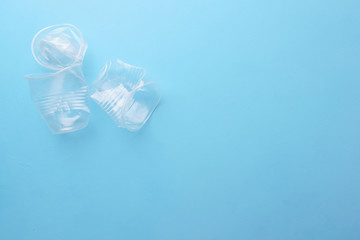 Crushed plastic cups on blue background. Garbage, environmental pollution, recycling and zero waste...