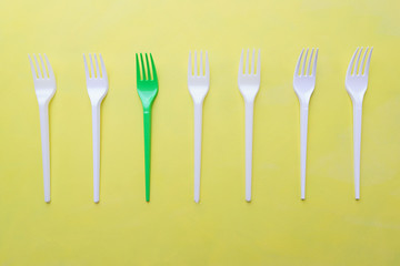 Ecological concept, zero waste. Recycling plastic forks on yellow background. Concious consumption, environment care