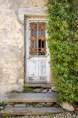 Fototapeta na wymiar door of an ancient abandoned house with a climbing plant