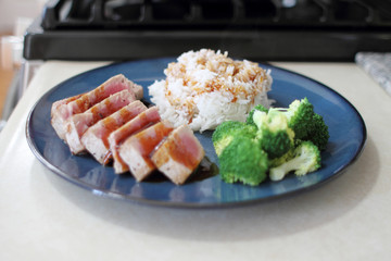 Ahi tuna sliced thin with teriyaki demi-glace, served with rice and broccoli.