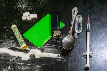 Fototapeta na wymiar cocaine, card, dollar, syringe, pills on a black table. Drugs close up.