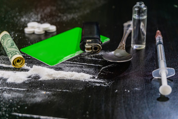 cocaine, card, dollar, syringe, pills on a black table. Drugs close up.