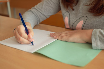 hand of a teenage girl writes with a ballpoint pen in a terad during a lesson at school