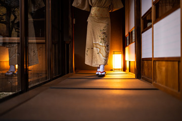 Traditional Japanese house ryokan, tatami mat floor and shoji sliding paper doors, woman in kimono and geta shoes tabi socks walking in corridor hall room