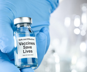 Healthcare concept with a hand in blue medical gloves holding a vaccine vial wtih the words Safe and Effective, Vaccines Save Lives, and does not cause autism