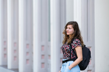 Fototapeta na wymiar Portrait of young woman female standing on street with backpack against architecture pattern modern columns of building in Montgomery, Alabama