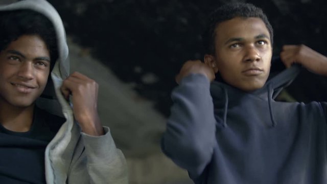 Cruel black teenagers putting on hoods going to commit crime, urban danger