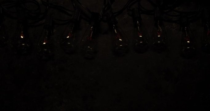 Antique string light bulbs flickering and flashing on old dark background.