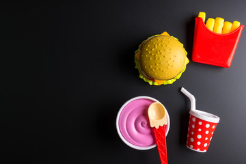 Plastic burger, French fries Fast food on black background. Children's toy. Concept of harmful artificial food. Plastic. Not organic. Not useful.