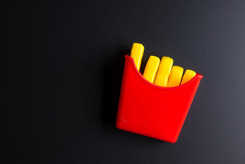 French fries Fast food on black background. Children's toy. Concept of harmful artificial food. Plastic. Not organic. Not useful.