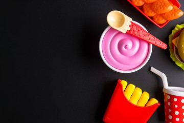 Plastic burger, French fries Fast food on black background. Children's toy. Concept of harmful artificial food. Plastic. Not organic. Not useful.