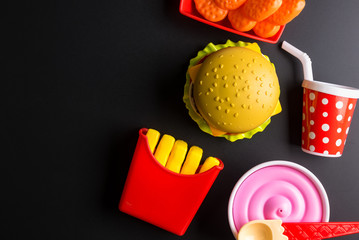 Plastic burger, French fries Fast food on black background. Children's toy. Concept of harmful artificial food. Plastic. Not organic. Not useful.