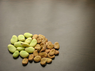 Dry and fresh broad beans seeds (Vicia faba) on wooden table close up.