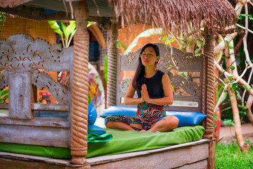 young natural and attractive Asian Chinese woman practicing yoga and meditation exercise sitting lotus pose outdoors at beautiful garden serene and calm in wellness
