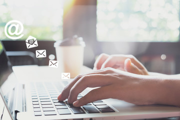 Hand of female using laptop computer sending e-mail message with email address symbol and envelope...