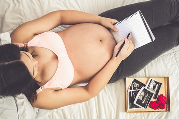 Pregnant woman feeling happy at home while taking care of her child. The young expecting mother...