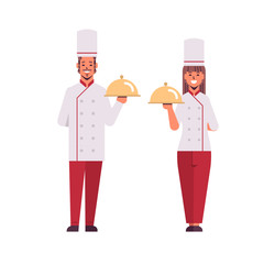 cooks couple professional chefs holding covered platters serving trays woman man restaurant workers in uniform standing together cooking food concept flat full length