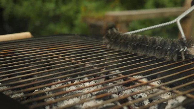 Cleaning a charcoal grill cooking grid with a wire brush