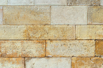 An old wall piled of stone yellow blocks. Natural background for design or texture.