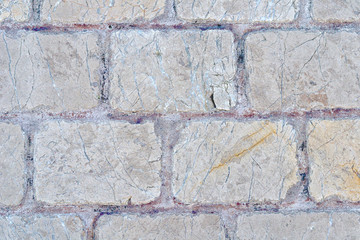 An old wall piled of  gray stone  blocks.