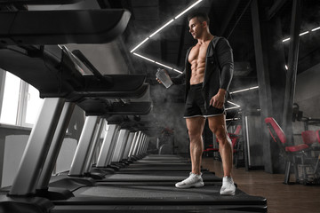 Obraz premium Athlete professional athlete man drinking from a shaker in the gym