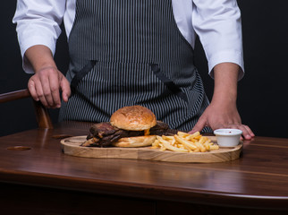 Obraz na płótnie Canvas a uniformed chef serves a meat dish on a wooden tray