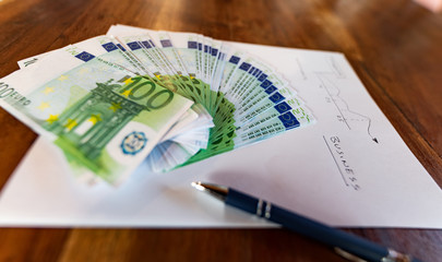 Soldi, banconote da cento euro su prospetto finanziario di crescita, indici borsa, PIL, Spread, cambi e credito