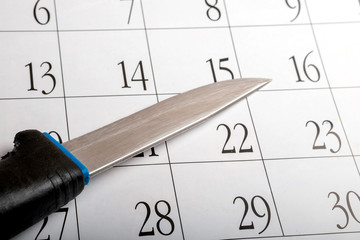 an old knife with a scratched blade on a calendar sheet with dates on it