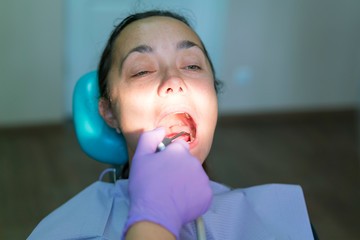 Dentist and patient in dentist office. Close-up of dental drill use for patient teeth in dentistry office in a dental treatment procedure. Woman having teeth examined at dentists