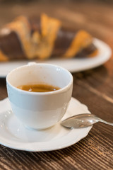 Fresh and tasty croissants with chocolate and cup of coffee on wooden background. copy space. vertical photo