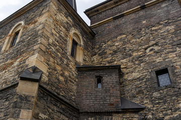 Part of the facade of a fancy building of old masonry with two turrets and a transition between them