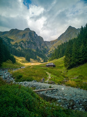 Wooden house at the base of the mountain with river flowing nearby