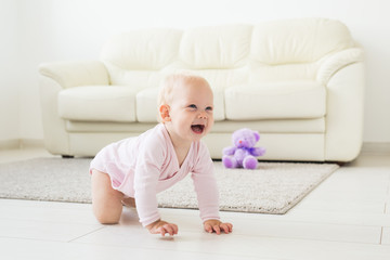 Fototapeta na wymiar Adorable baby girl learning to crawl in white sunny room.