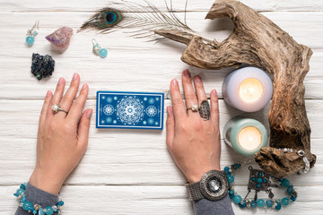 Fortune teller woman and a blue tarot cards over white wooden table background.