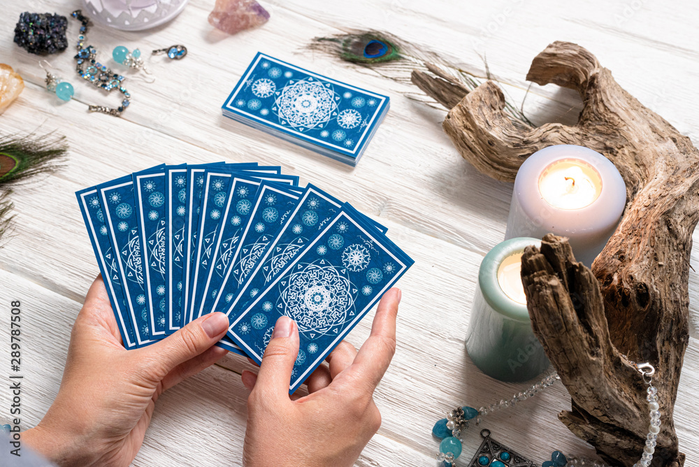 Wall mural fortune teller woman and a blue tarot cards over white wooden table background.